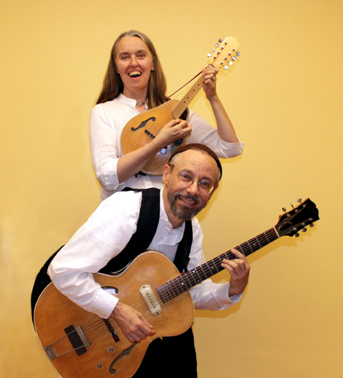 Vertical photo of Ensemble M’chaiya (tm) as a duet – Jutta Distler, standing in back – mandolin, Terran Doehrer, in front – guitar. Photo by Betina Distler. Photo copyright 2012 Modal Music, Inc. (tm). All rights reserved.